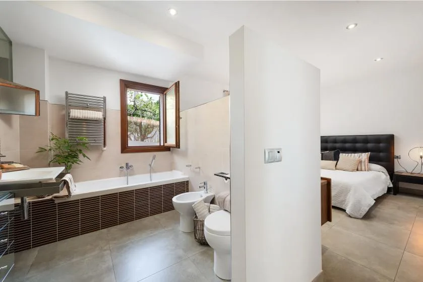 A bathroom with a bathtub opens onto a bedroom with a bed.
