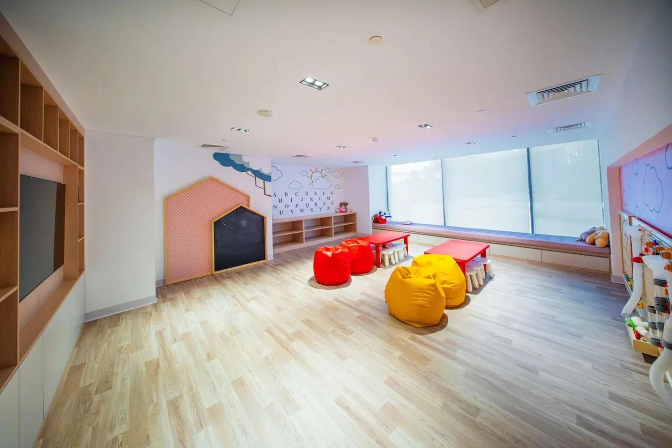 A bright playroom with colorful beanbag seating and large windows.