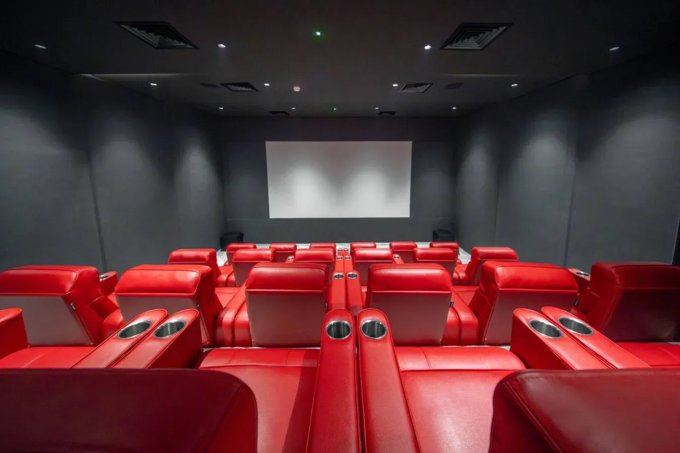 A private theater with rows of red seating facing a large screen.
