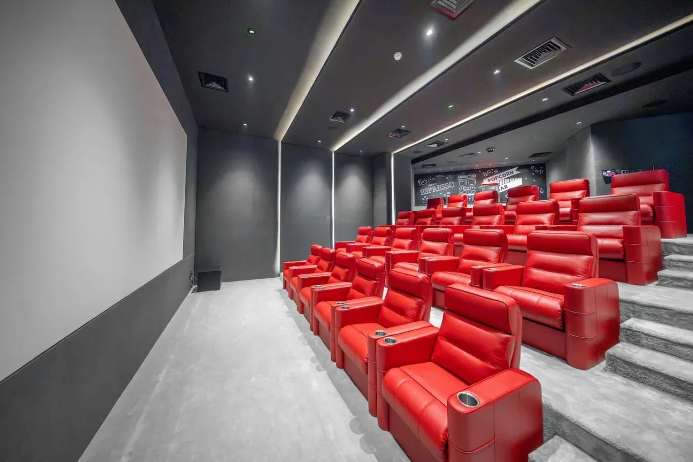 A small cinema auditorium with rows of red seats and a large screen.