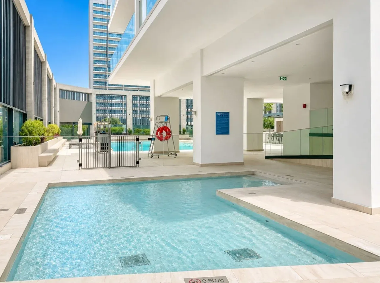 An outdoor swimming pool sits beside a modern white building.
