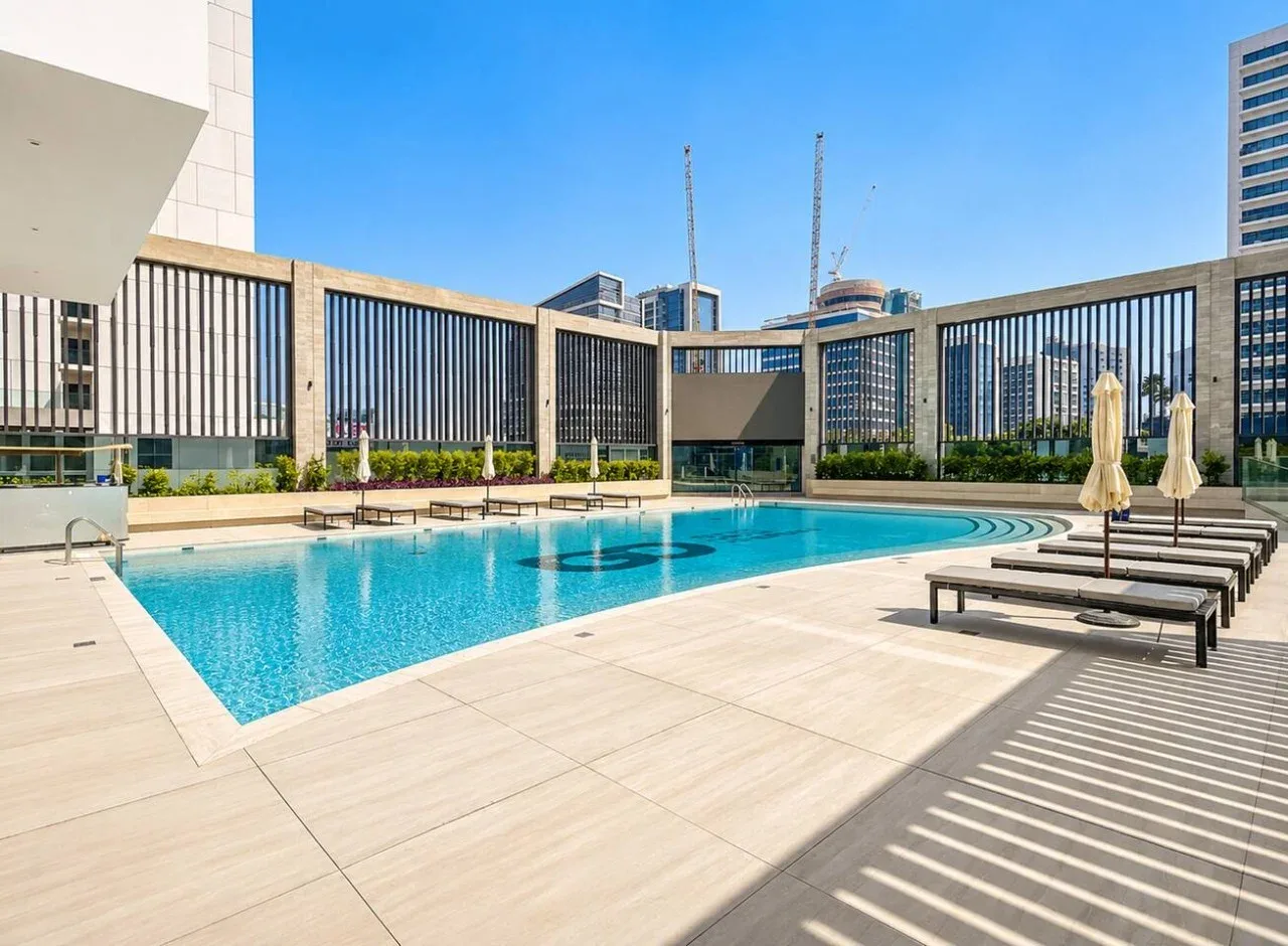 An outdoor swimming pool sits beside a paved deck with loungers.