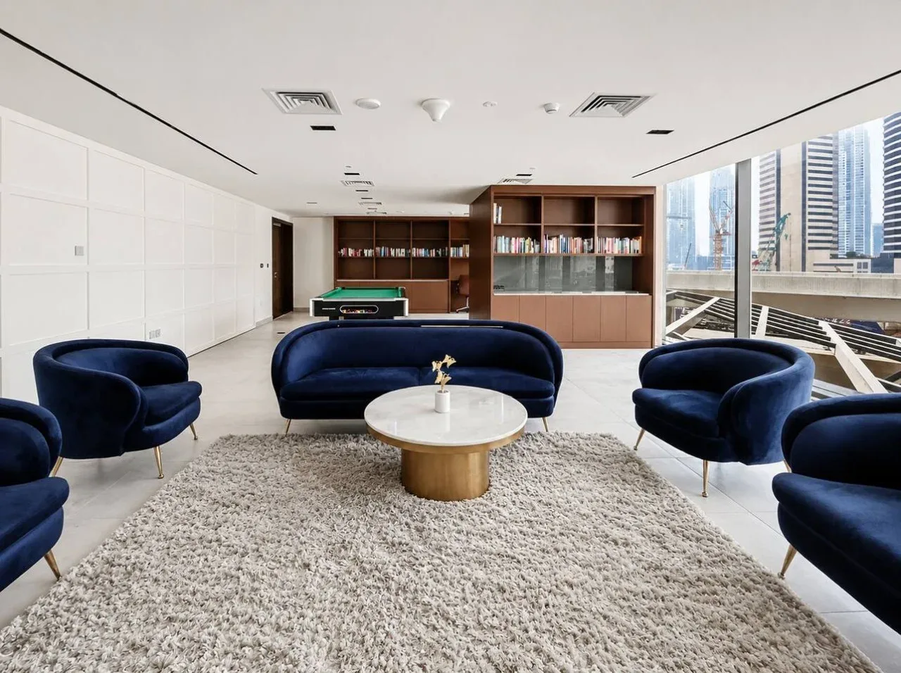 A bright lounge with blue seating around a low coffee table.