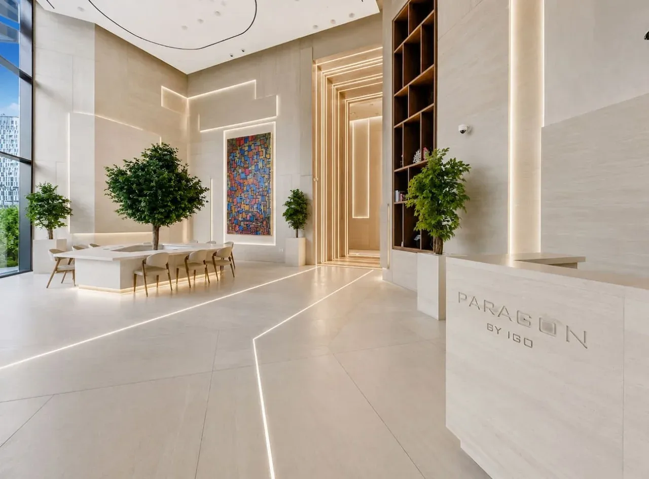 A bright reception area with a front desk, dining table, and indoor plants.