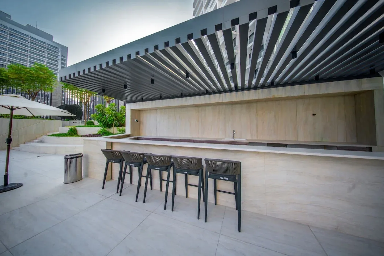 An outdoor bar counter with seating beneath a slatted canopy.