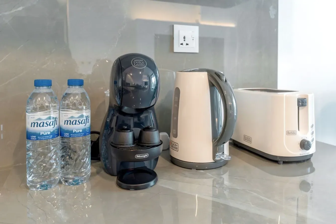 A countertop beverage station with a coffee machine, kettle, and toaster.
