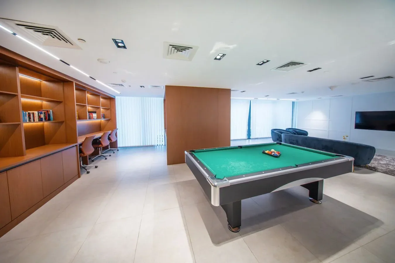 A game room with a pool table, built-in shelving, and seating.