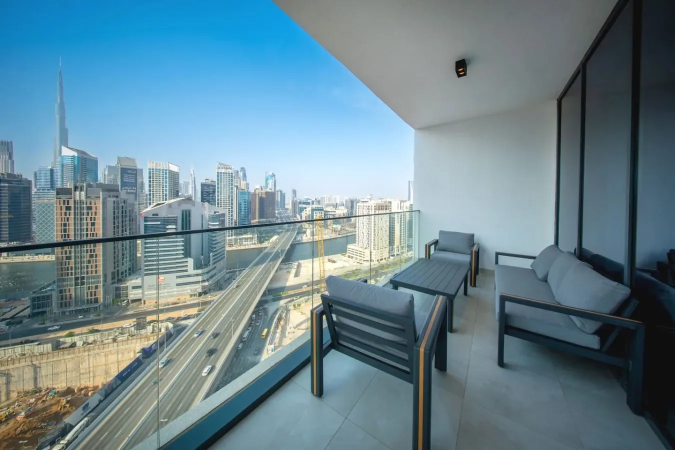 A balcony seating area overlooks a city skyline and multilane roads.