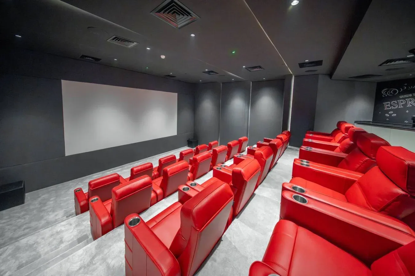A small theater room with rows of red seating facing a projection screen.