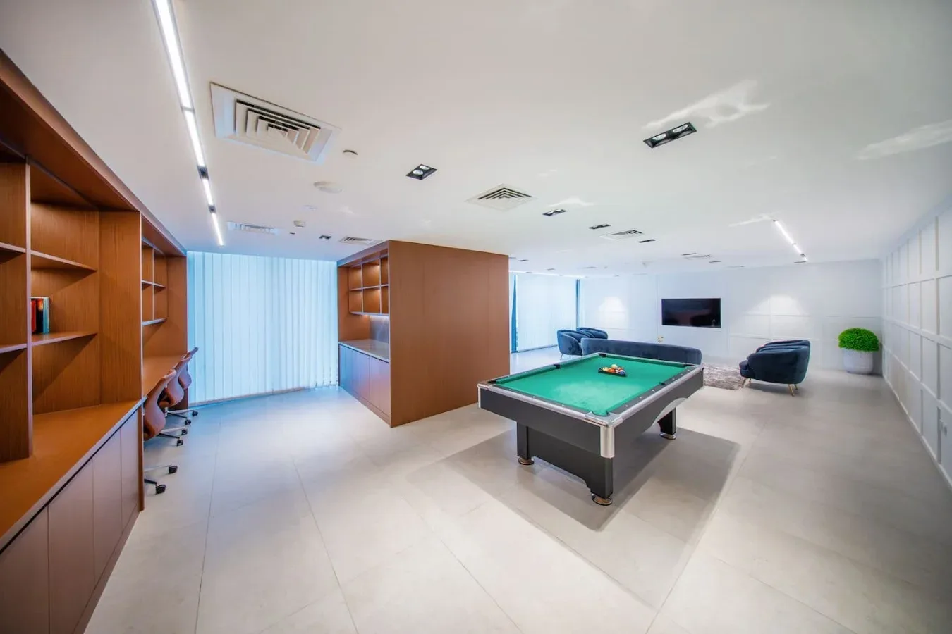 A recreation room features a green-felt pool table and built-in wooden shelving.