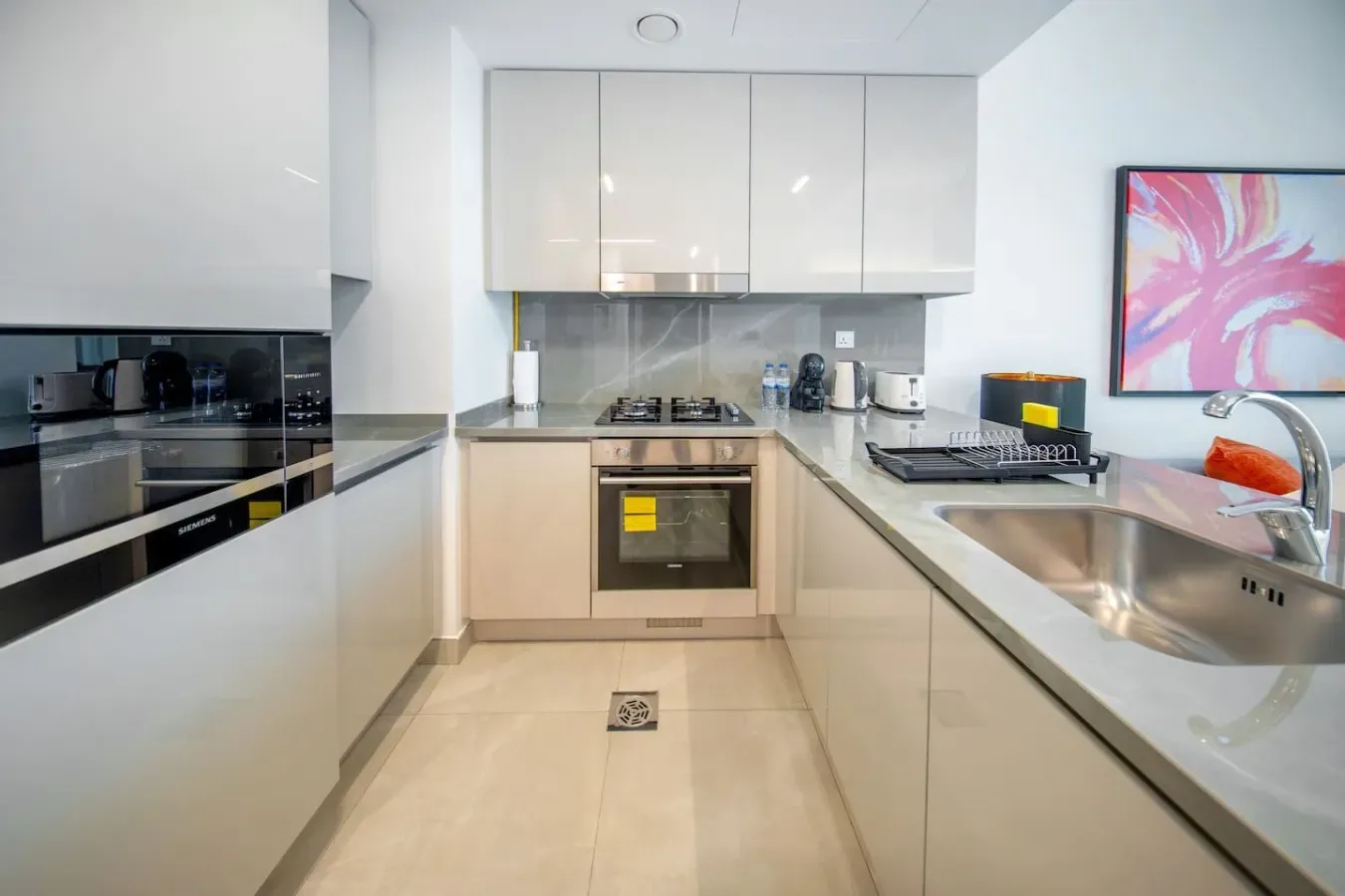 A modern kitchen with white cabinetry, a cooktop, and a sink.