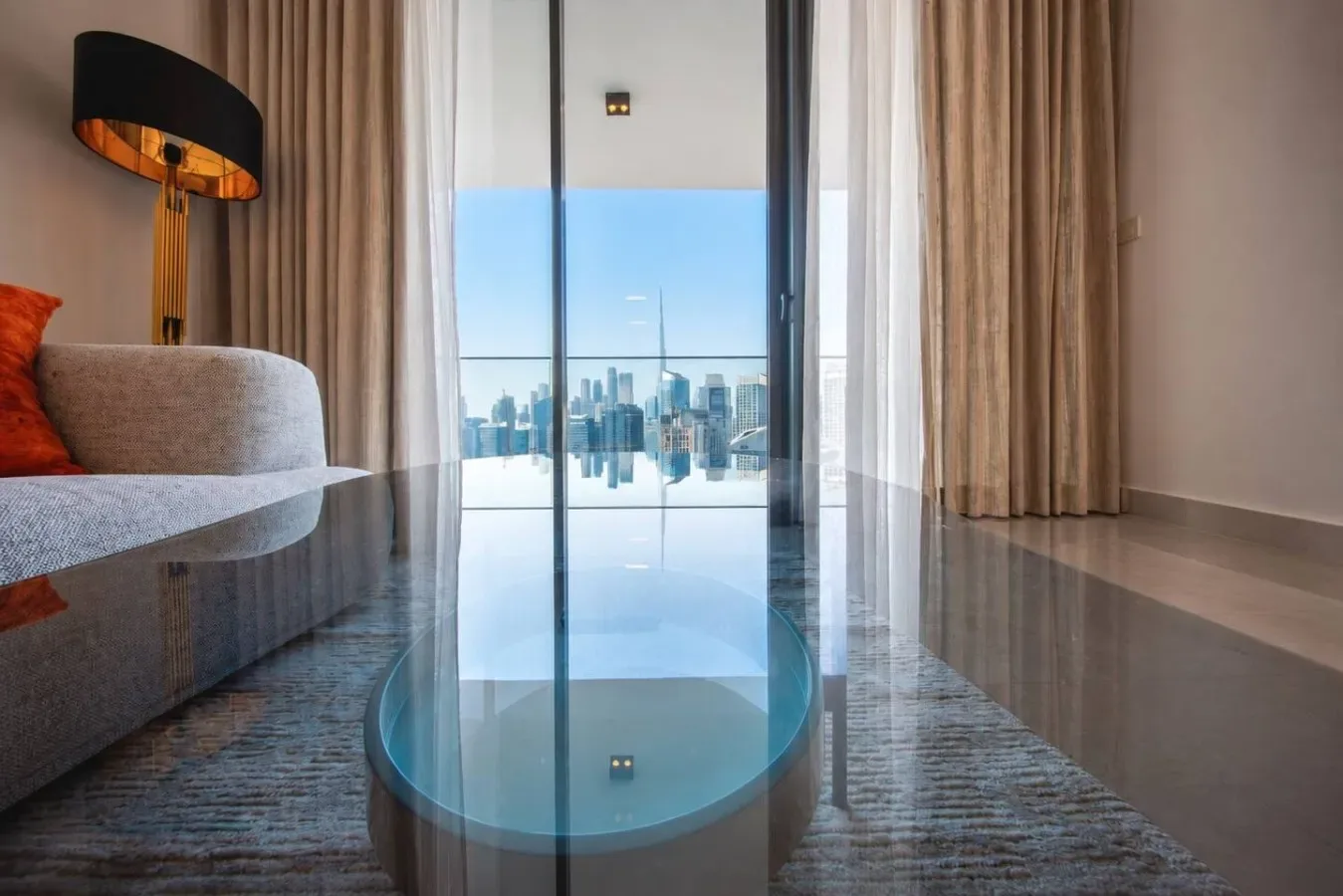 A living room opens onto a balcony with a city skyline view.