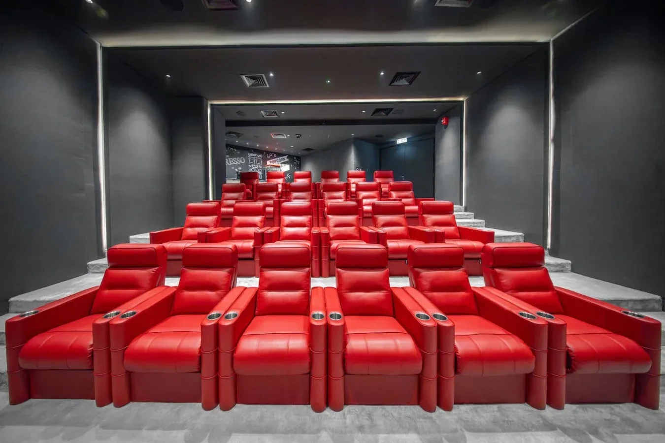 A theater auditorium with rows of red seats facing the screen.