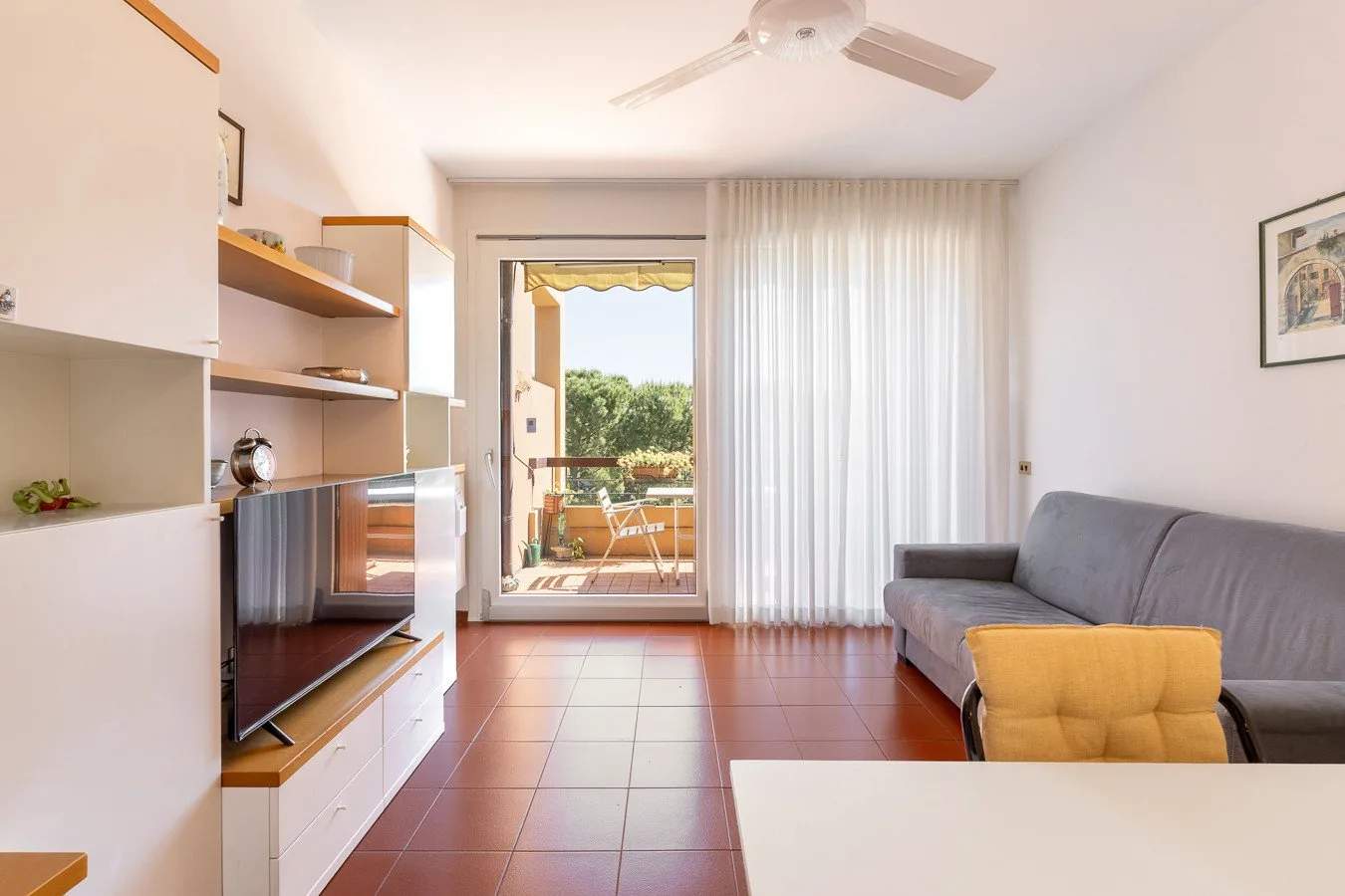 Una sala luminosa con asientos y una puerta abierta al balcón.