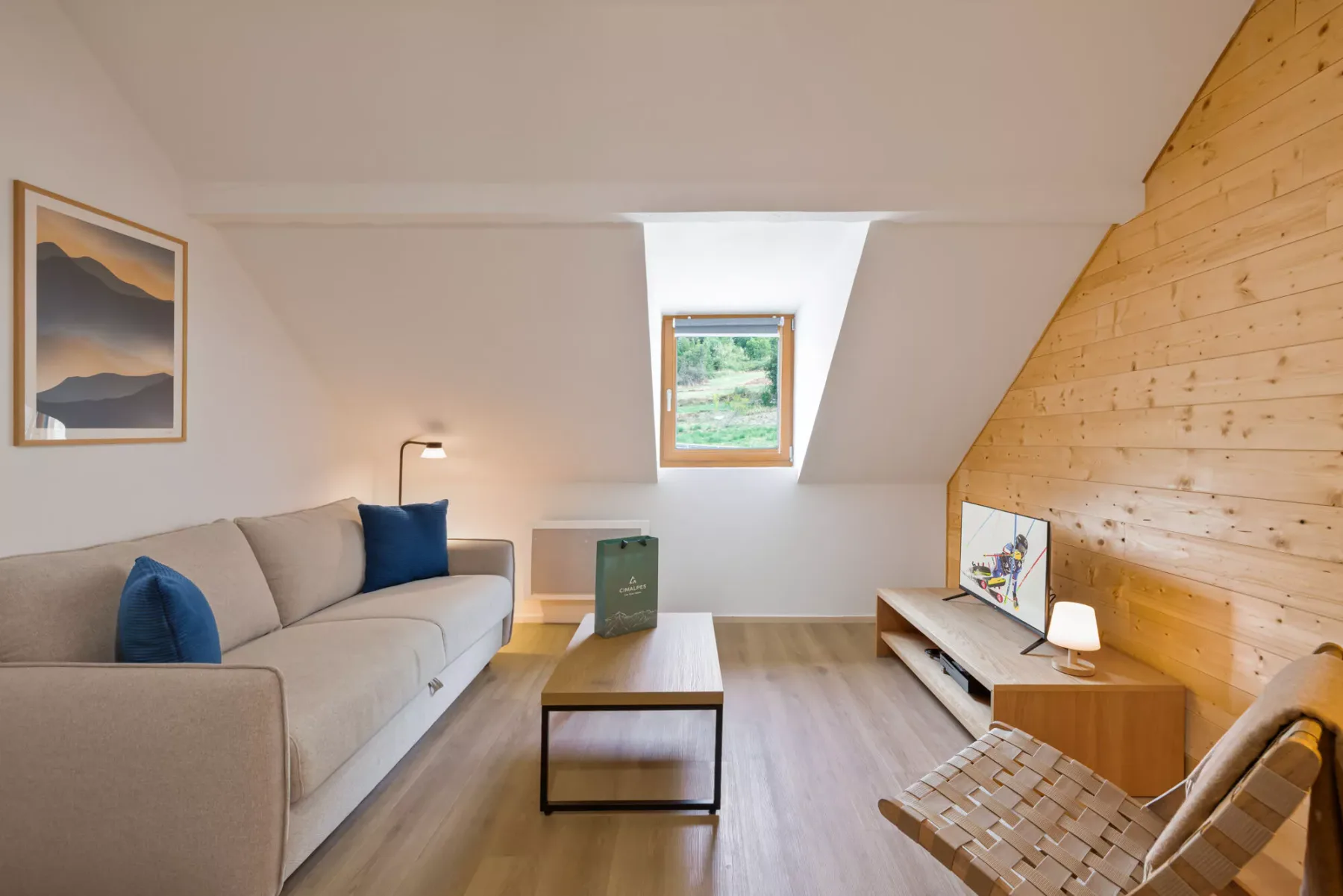 Una luminosa sala de estar abuhardillada con sofá y mesa de centro bajo una claraboya.
