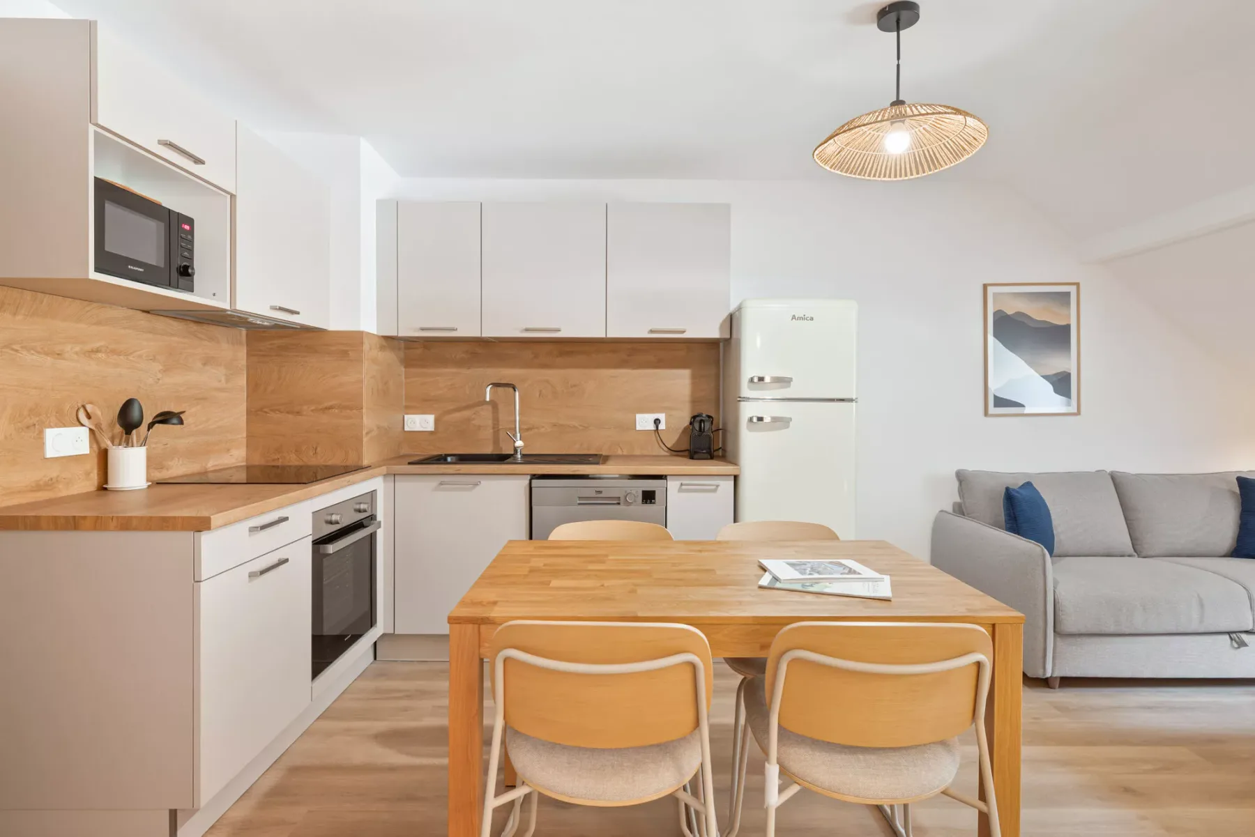 Una cocina y comedor de concepto abierto, con una mesa de madera y asientos junto a un sofá.