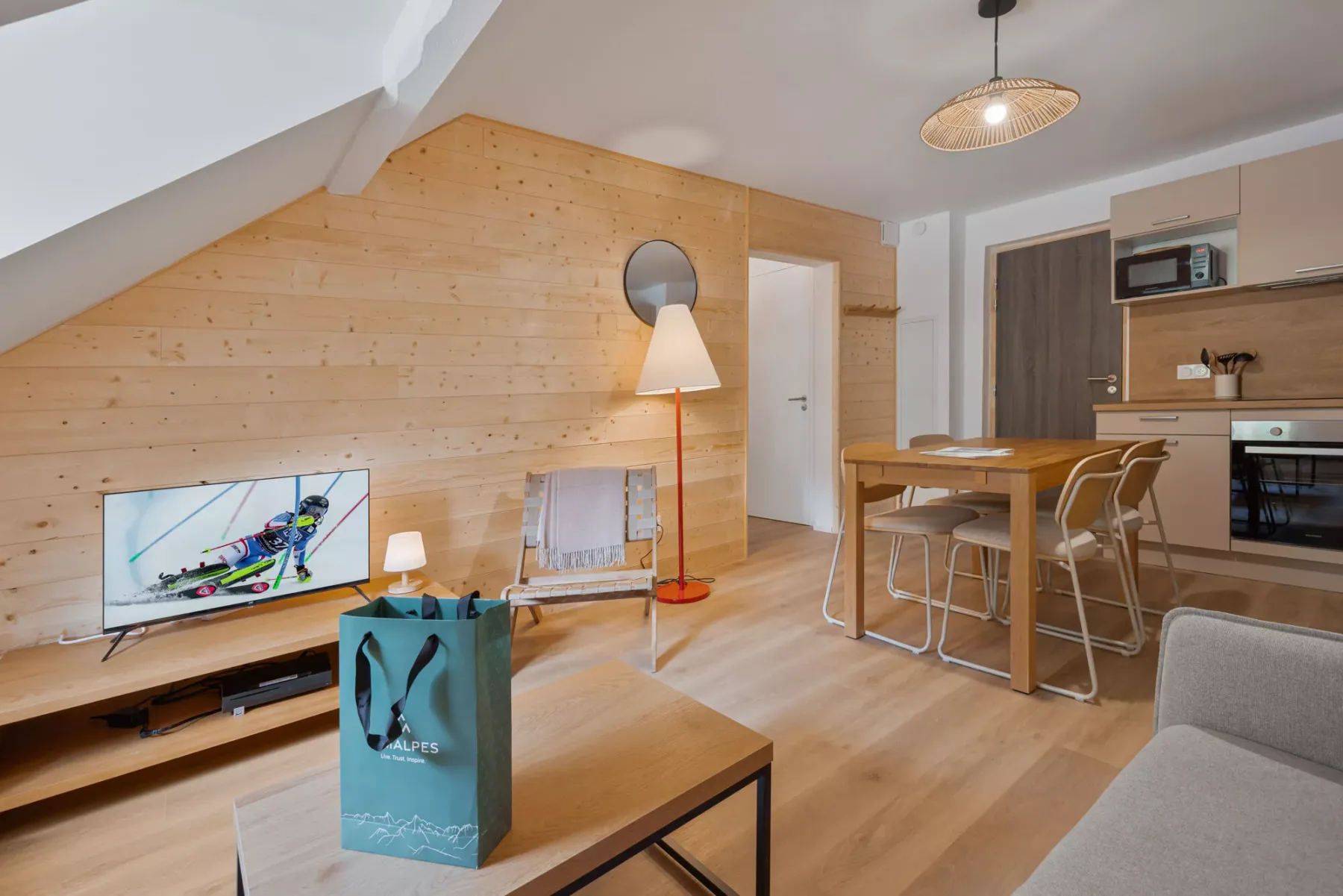 A bright open-plan living area with a dining table and kitchenette.