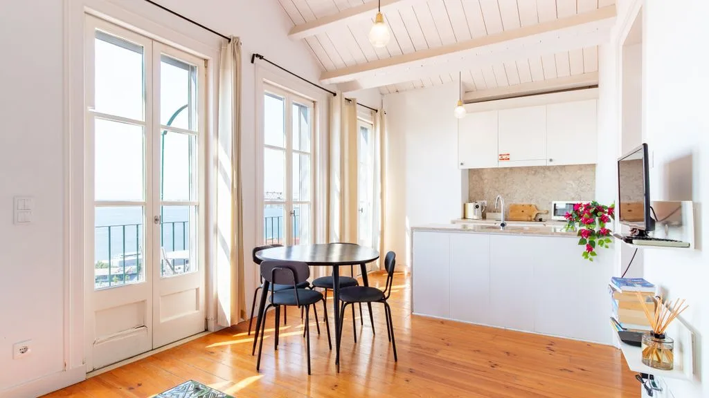 Una estancia luminosa y diáfana con comedor y cocina compacta junto a ventanas altas.