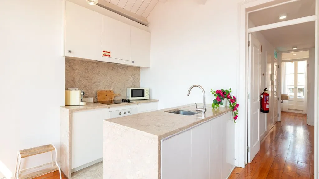 Una cocina luminosa con encimera, fregadero y armarios blancos.