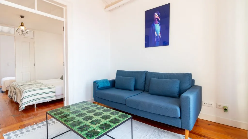 Una sala de estar con asientos azules y una mesa de centro con estampado verde.