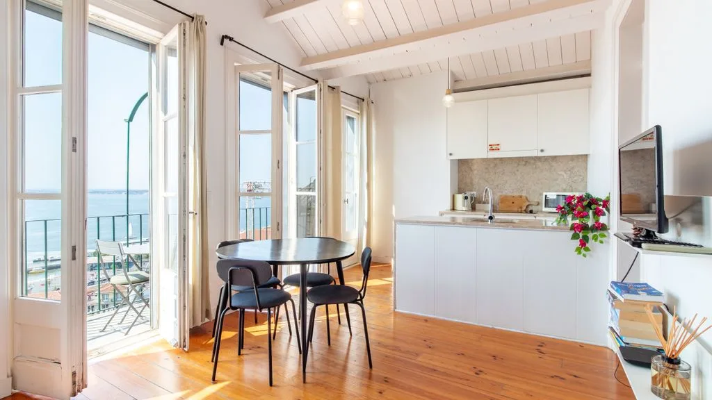 Un comedor luminoso da a un balcón junto a una cocina compacta.