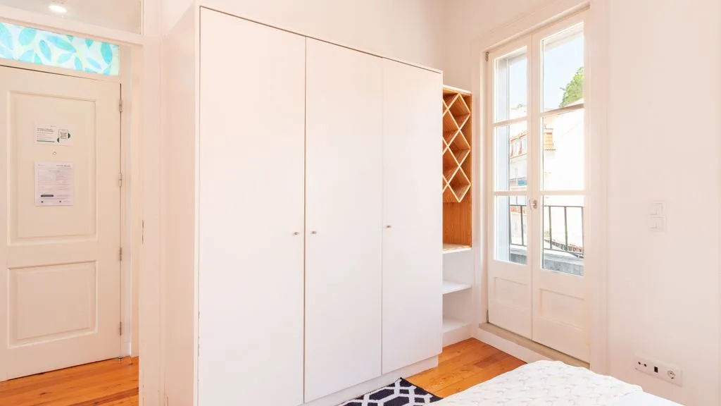 Una habitación luminosa con un armario blanco grande junto a una ventana.