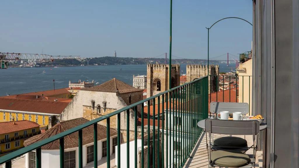 Una terraza estrecha da a edificios de tejados rojos y un río ancho.