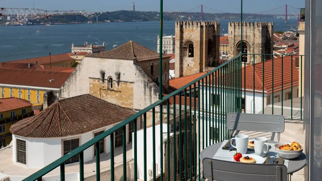 Una mesa en la terraza mira hacia tejados rojizos y un río amplio.