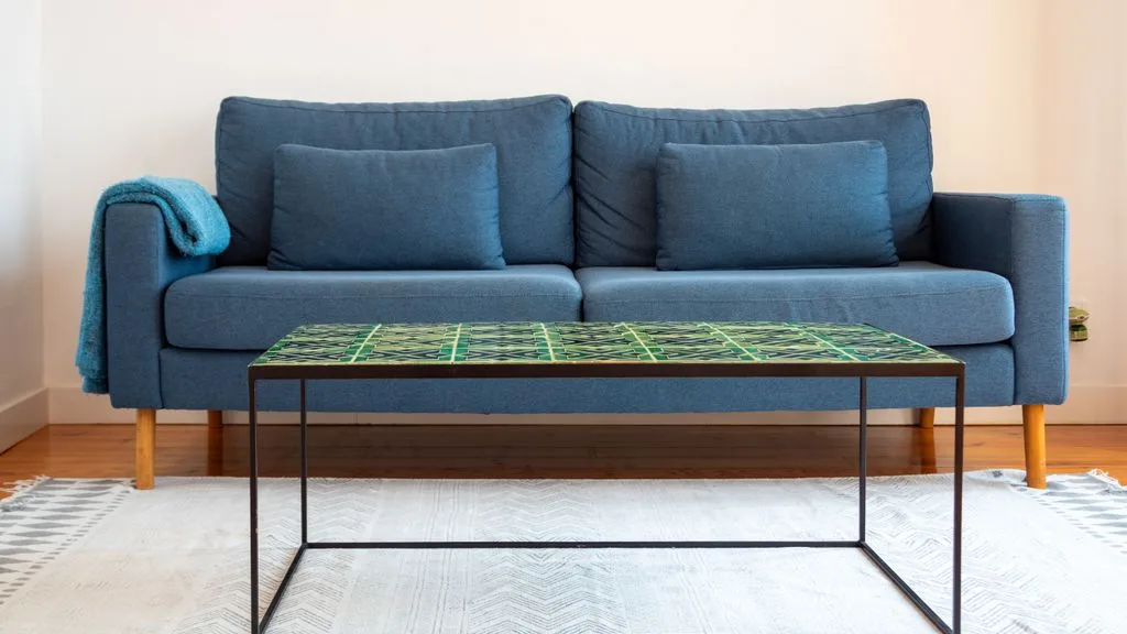 Una sala de estar con asientos azules y una mesa de centro con tablero de vidrio.