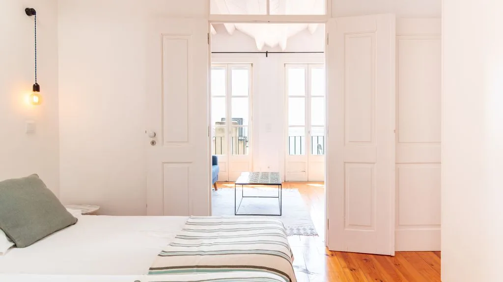 Un dormitorio luminoso se abre a una zona de estar mediante puertas dobles.