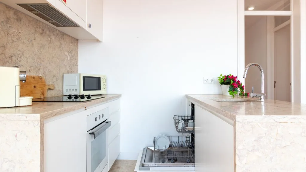 Una cocina luminosa con encimeras claras y un lavavajillas.