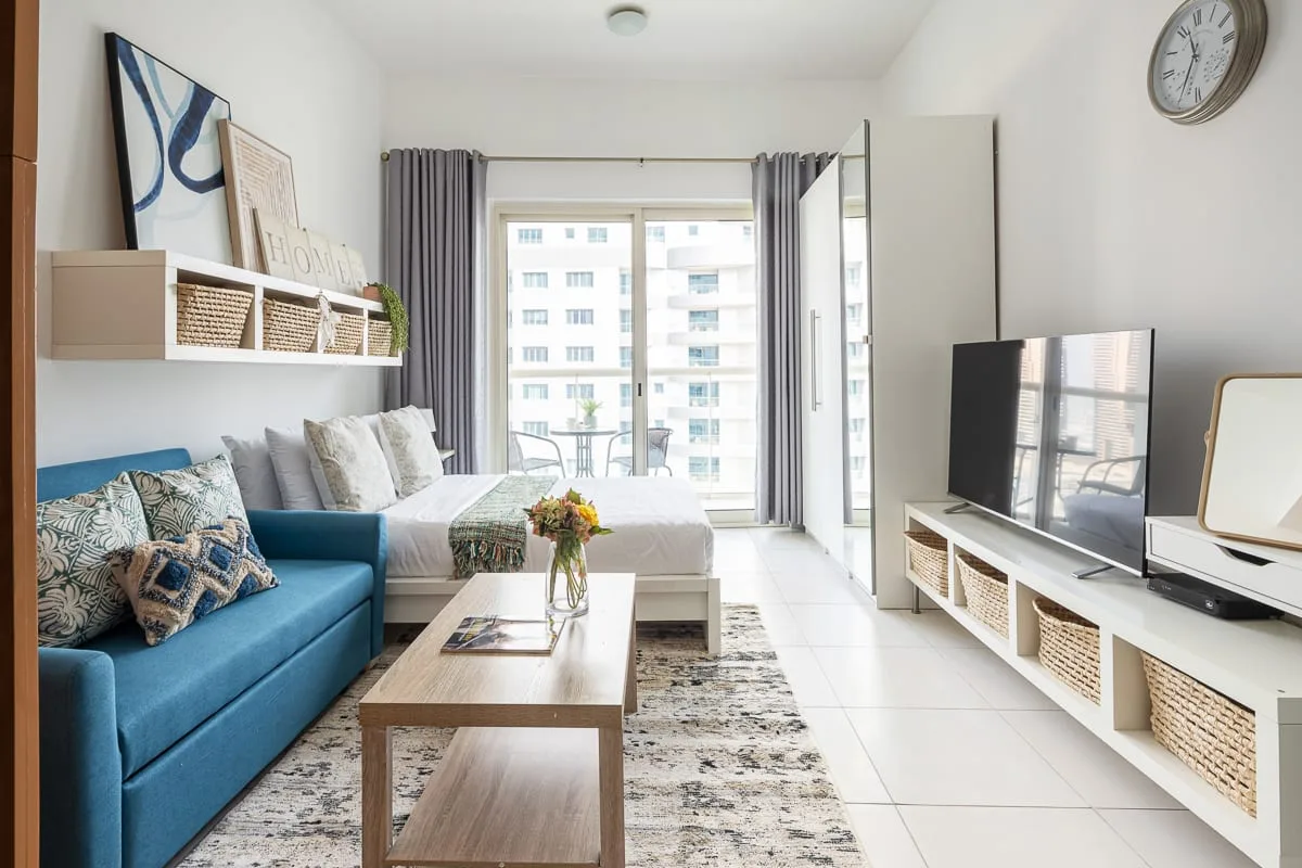A bright living room with seating, a television, and large windows.