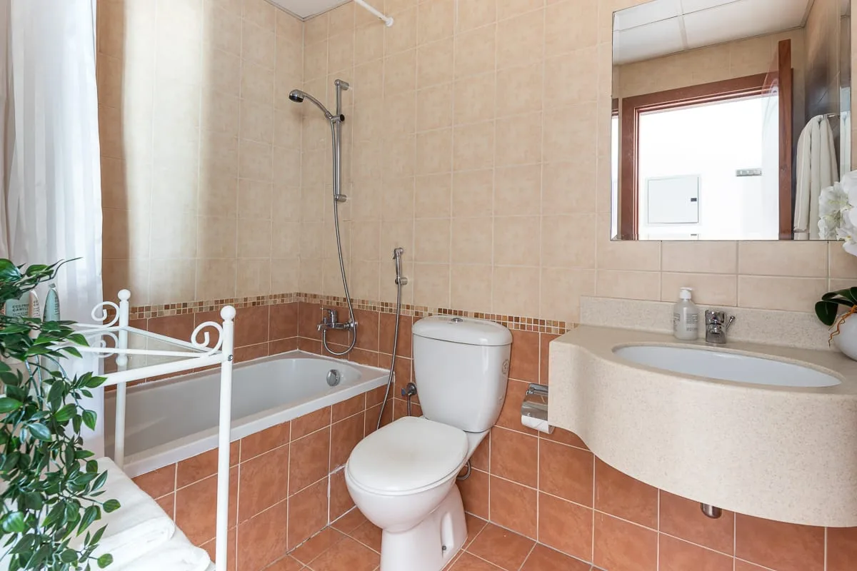 A tiled bathroom with a bathtub, toilet, and curved vanity.