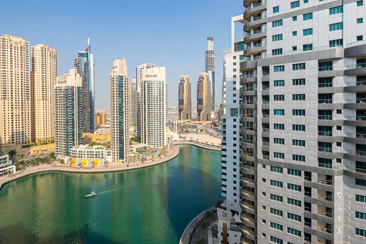A canal curves past high-rise buildings in a dense urban waterfront scene.