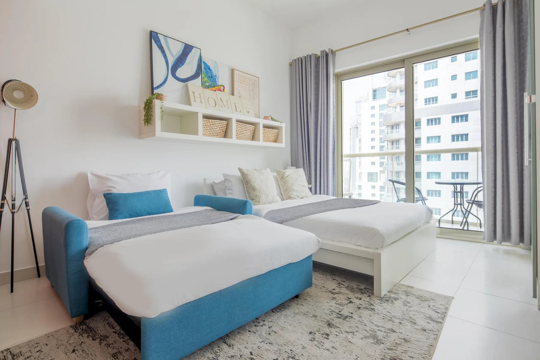 A bright bedroom with two beds beside a large window.