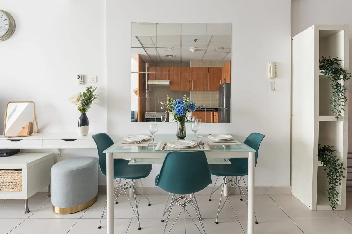 Un comedor luminoso con una mesa de vidrio y asientos color turquesa.