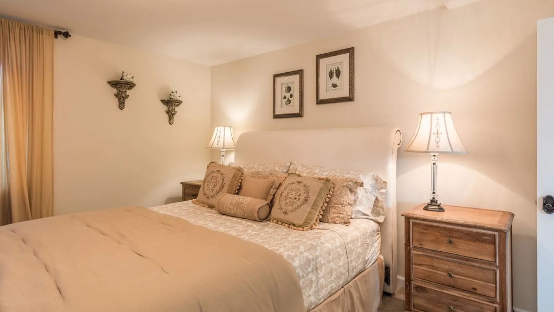 Un dormitorio con una cama, mesitas de noche y cuadros en la pared.