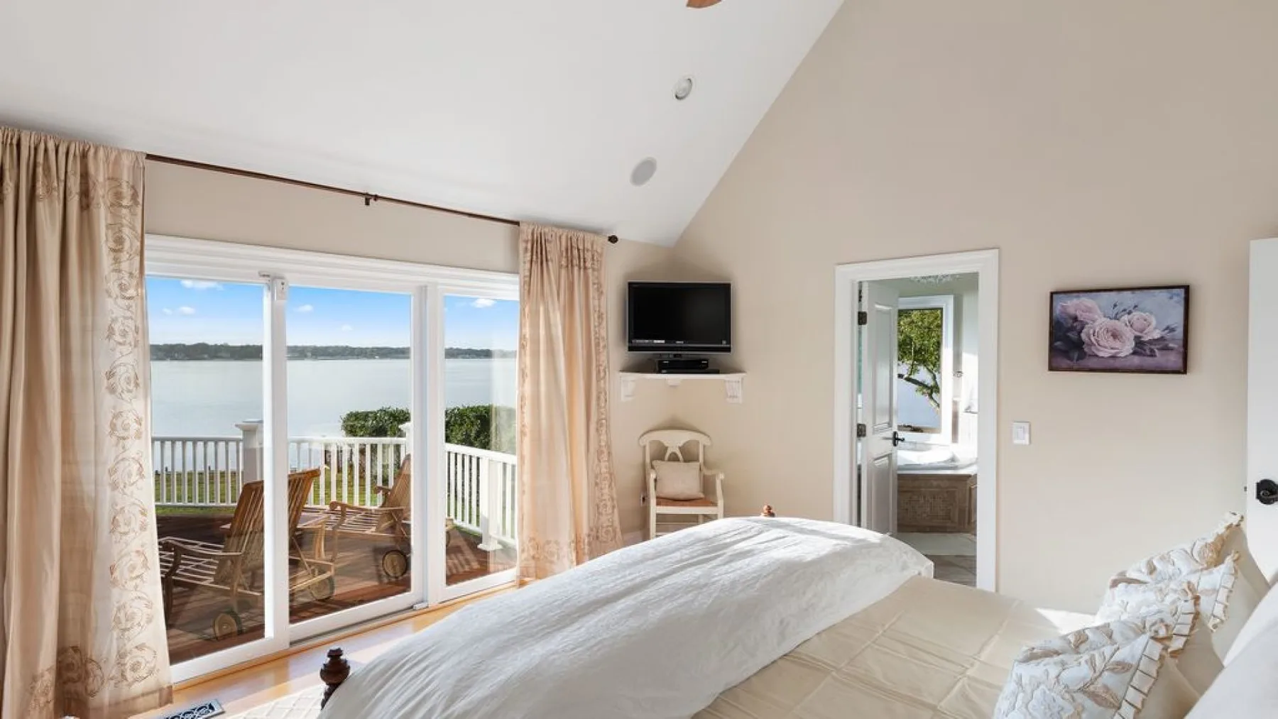 Un dormitorio con una cama, puertas de vidrio y vistas al agua.