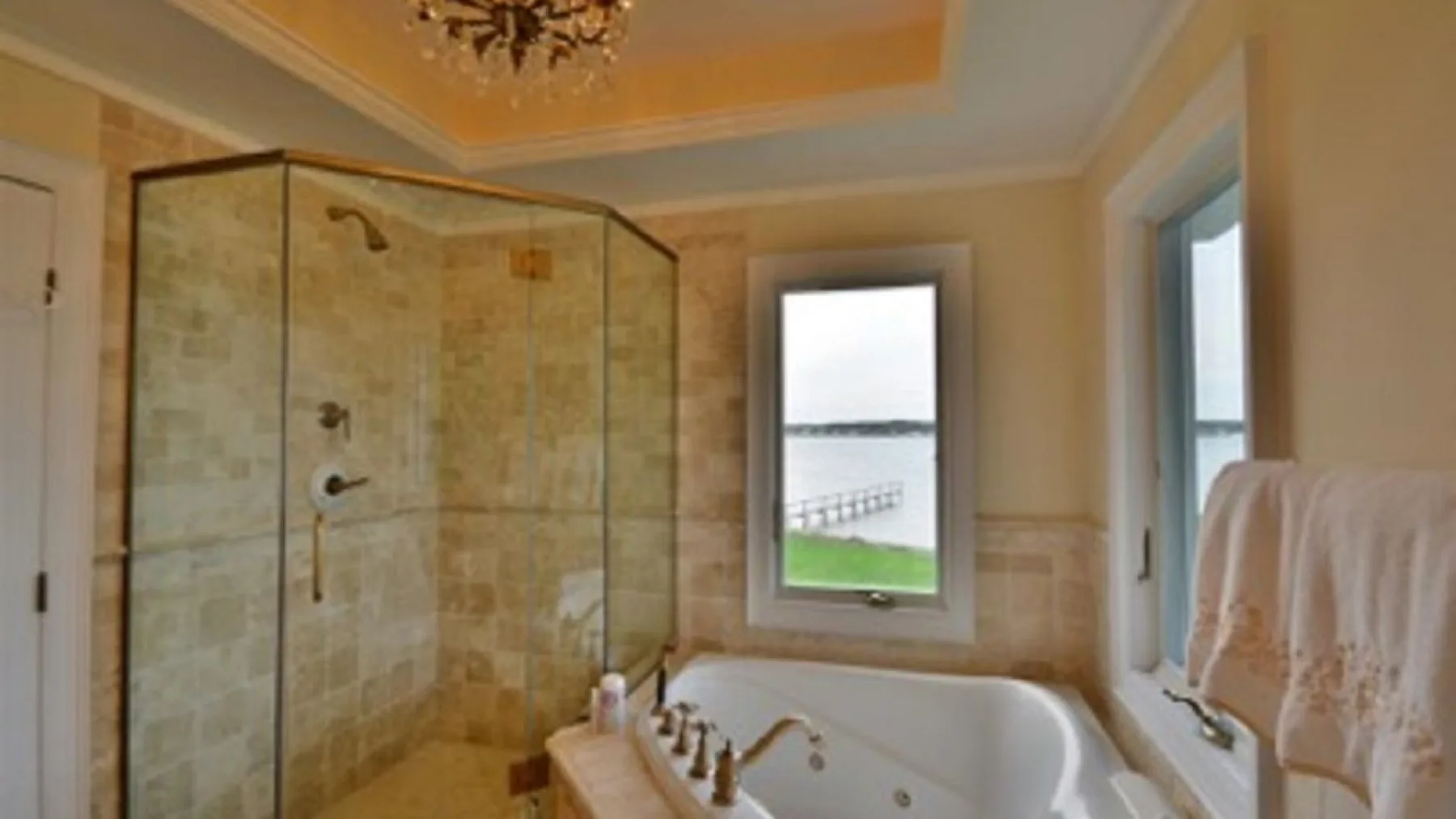 Un baño con ducha de vidrio y bañera junto a las ventanas.