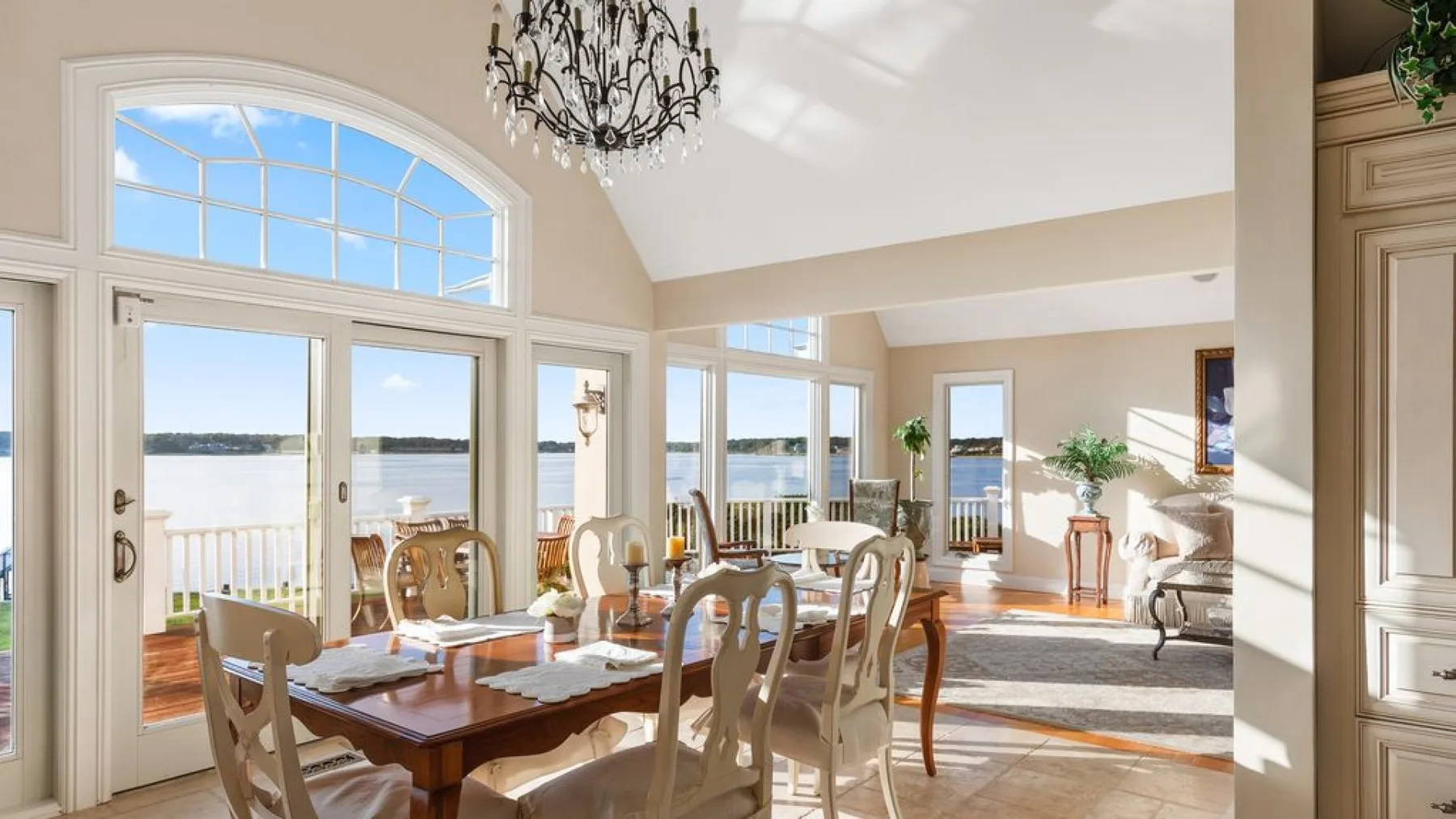 Un comedor luminoso con una mesa de madera junto a grandes ventanales con vistas al agua.