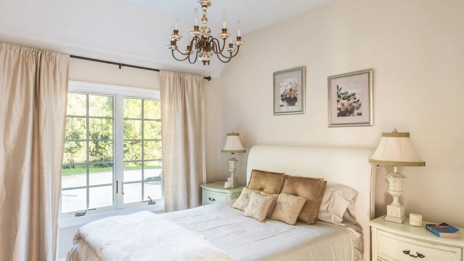 Un dormitorio luminoso con una cama grande y puertas de vidrio que dan a un jardín.