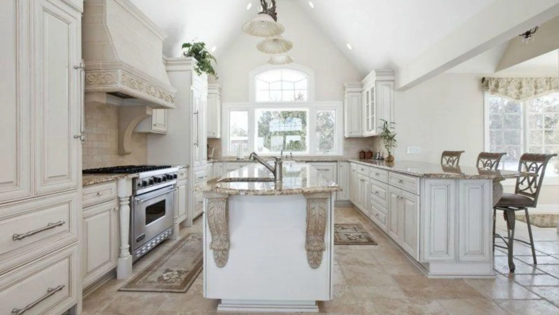 Una cocina luminosa con una isla central, gabinetes blancos y ventanas grandes.