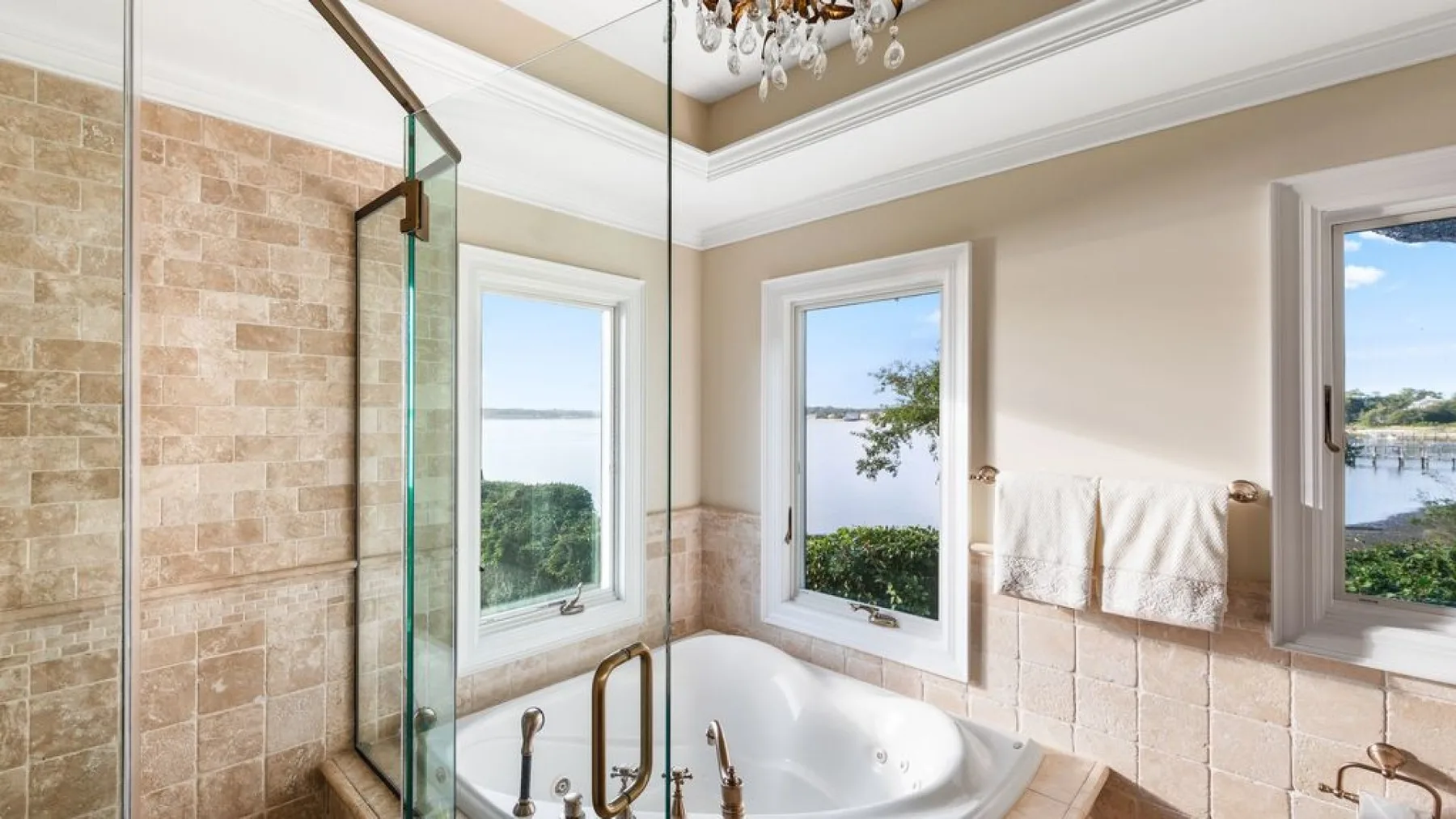 Un baño con bañera integrada, paredes revestidas de azulejos y varias ventanas.