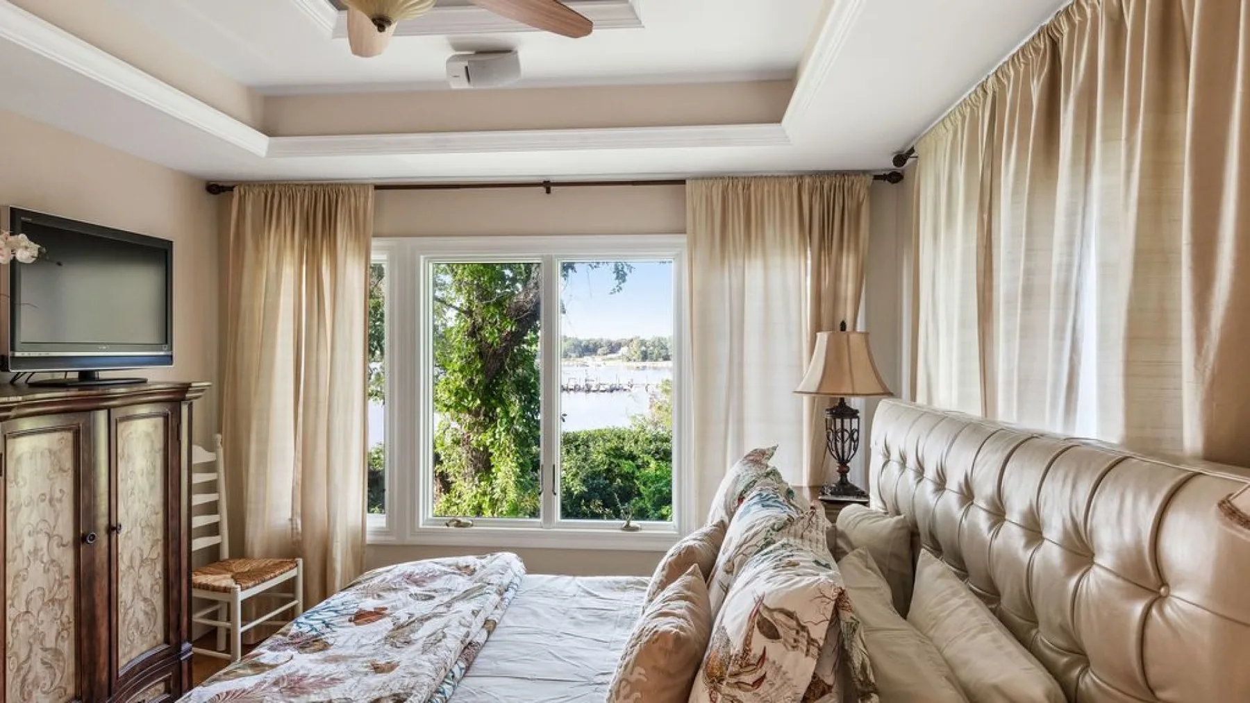 Un dormitorio con una cama y asientos junto a una ventana con vistas al agua.