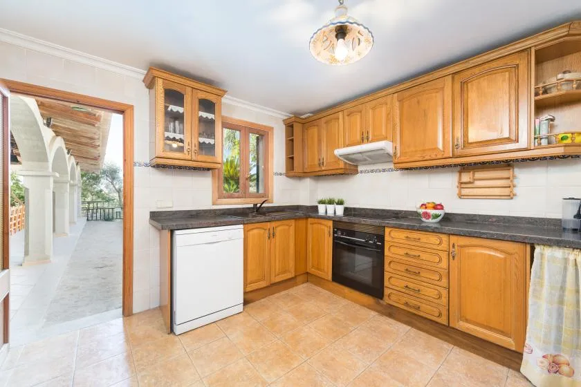 A kitchen with wooden cabinets, dark countertops, and a dishwasher.