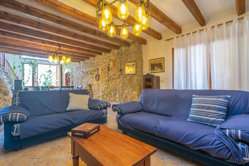A living room with blue seating and a wooden coffee table beneath exposed beams.