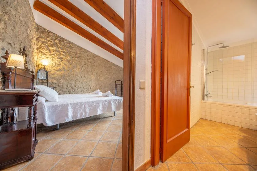 A bedroom with a bed and a tiled bathroom visible through the open doorway.