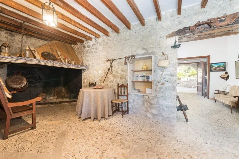 A rustic stone interior with a large fireplace and a round table.