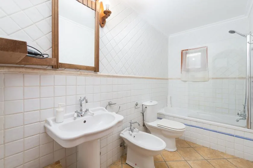 A tiled bathroom with a sink, toilet, bidet, and bathtub.