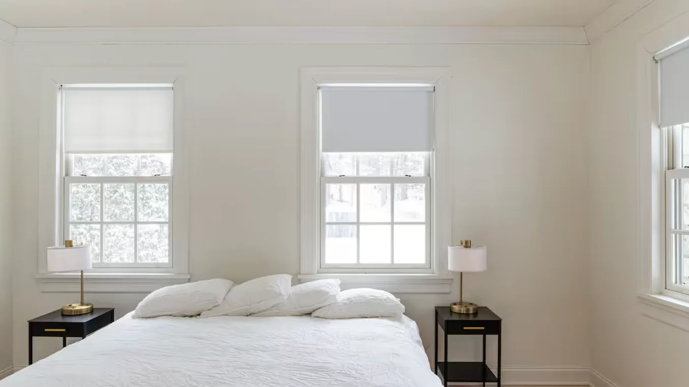 A bedroom with a bed between two windows and matching bedside tables.